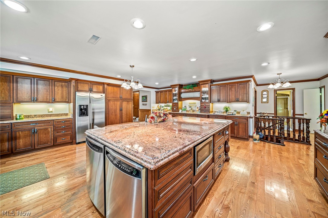 8801 Bunker Road Orwell, OH 44076 - Photo 21 of 50 Kitchen with a chandelier, ornamental molding, hanging light fixtures, stainless steel appliances, and light stone counters