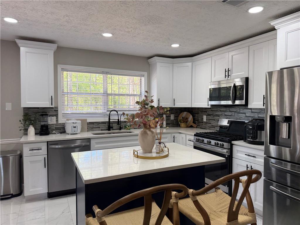 934 Bay Ridge Drive Lawrenceville, GA 30045 - Photo 76 of 78 a kitchen with stainless steel appliances granite countertop a stove a sink a microwave a refrigerator and cabinets