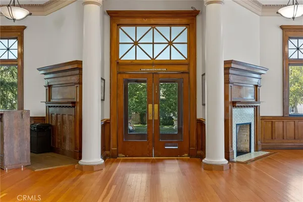 an empty room with windows wooden floor and front door