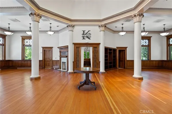 an empty room with wooden floor fireplace and chandelier