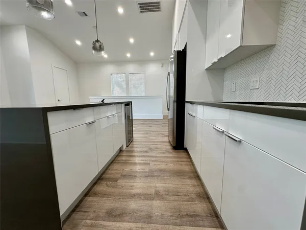 a view of a kitchen with kitchen island a sink wooden floor and stainless steel appliances