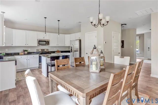 a kitchen with stainless steel appliances granite countertop a stove a kitchen island a dining table and chairs