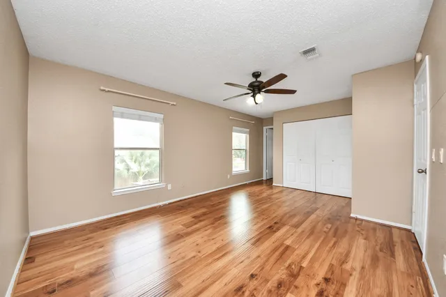 a view of empty room with wooden floor and fan