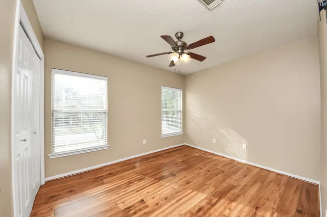 a view of a room with wooden floor and a ceiling fan