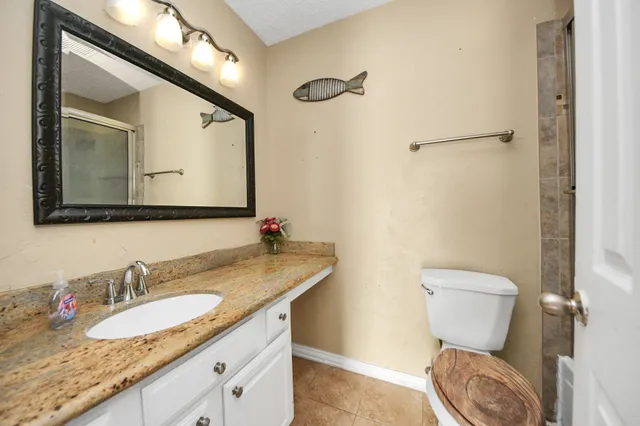 a bathroom with a granite countertop toilet sink and mirror