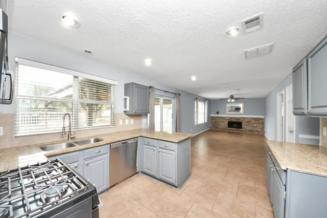 a large kitchen with stainless steel appliances granite countertop a sink and cabinets