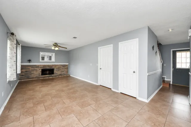 an empty room with windows and fireplace