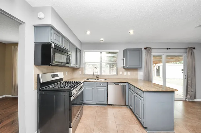 a kitchen with stainless steel appliances granite countertop a stove a sink and a microwave