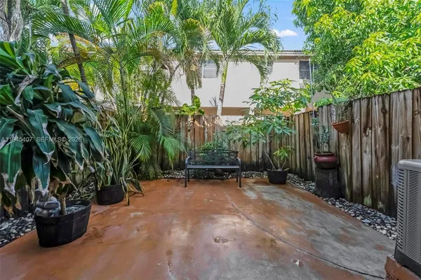 a view of a backyard with potted plants and large trees