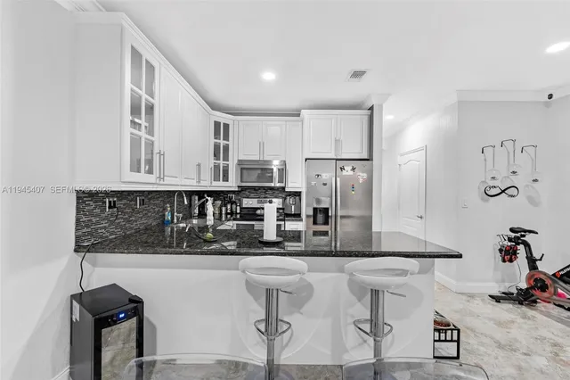 a kitchen with stainless steel appliances kitchen island granite countertop a refrigerator and cabinets