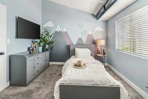 a bedroom with a bed table flowerpot and flat screen tv