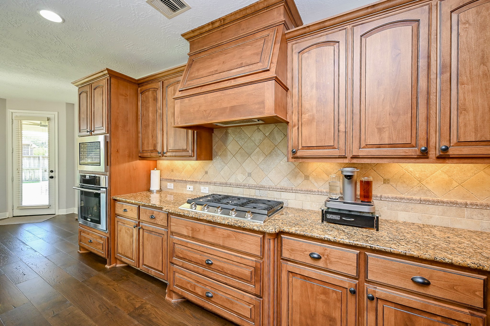17607 Astrachan Road Richmond, TX 77407 - Photo 12 of 50 a kitchen with stainless steel appliances granite countertop a sink a stove cabinets and wooden floor