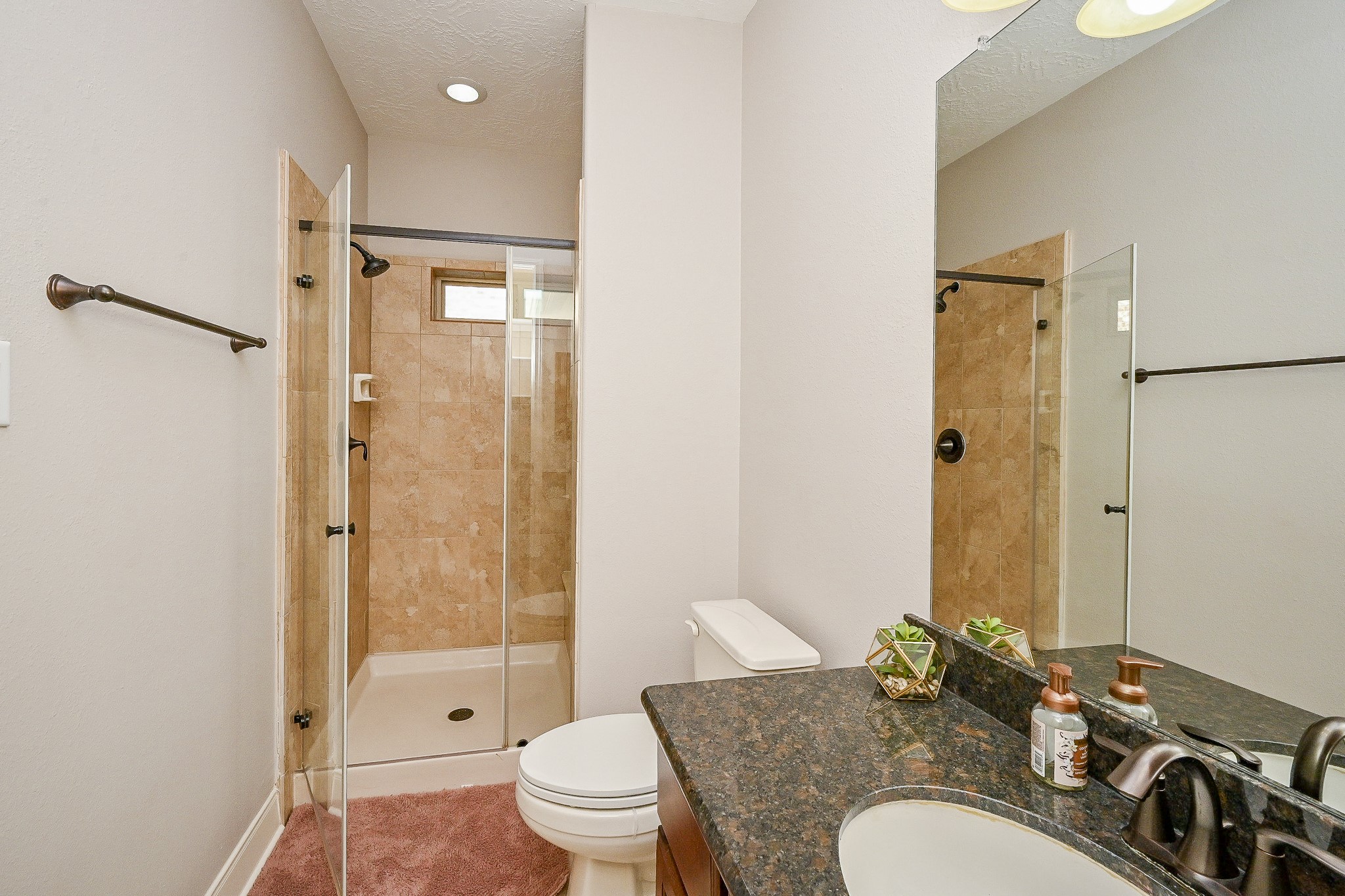 17607 Astrachan Road Richmond, TX 77407 - Photo 29 of 50 a bathroom with a granite countertop sink toilet mirror and shower
