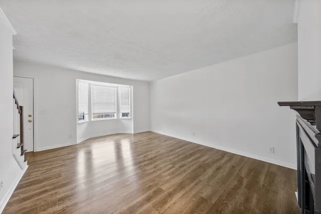 a view of a livingroom with wooden floor and a fireplace