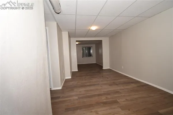 a view of a hallway with wooden floor and a bathroom