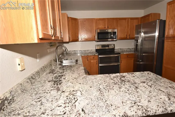 a kitchen with granite countertop a refrigerator sink and microwave