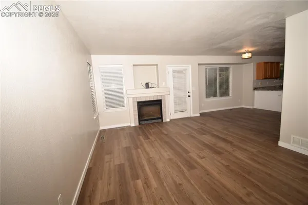a view of empty room with wooden floor and fireplace