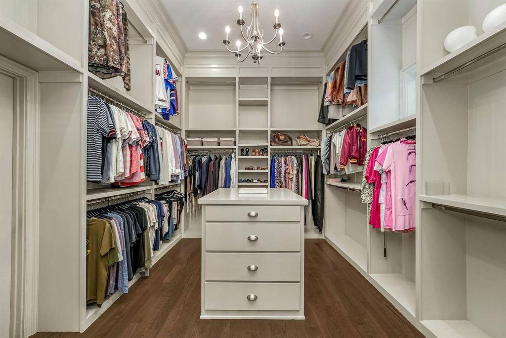 12114 Prestonridge Road Dallas, TX 75230 - Photo 29 of 40 Custom walk-in closet featuring built-in cabinetry, varied hanging rods, open shelving, and a central island with drawers