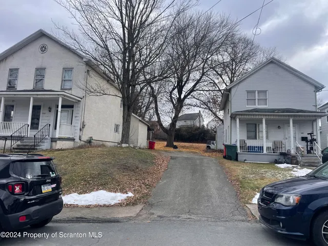 a view of a white house with a yard and a car parked in front of it