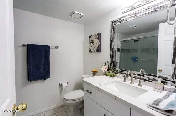 a bathroom with a granite countertop sink toilet and mirror