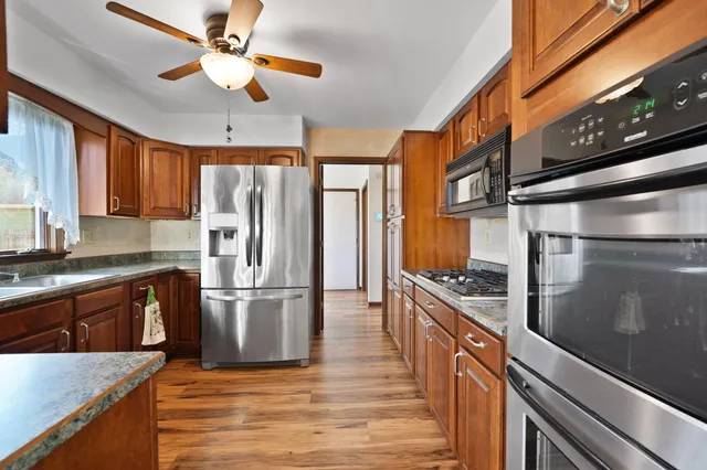 a kitchen with stainless steel appliances granite countertop a refrigerator a stove and a sink
