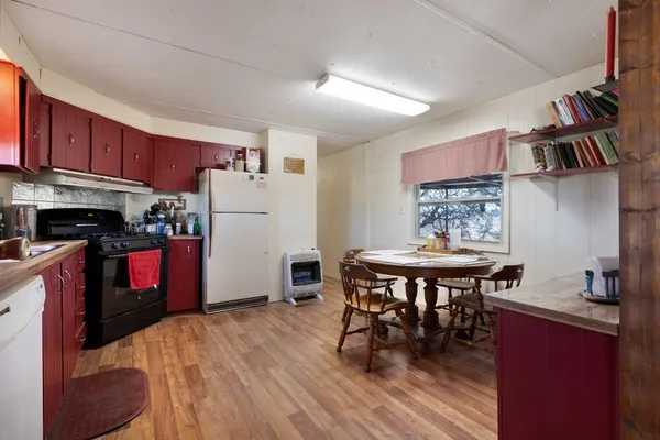 a kitchen with stainless steel appliances granite countertop a stove a refrigerator a kitchen island a dining table and chairs with wooden floor