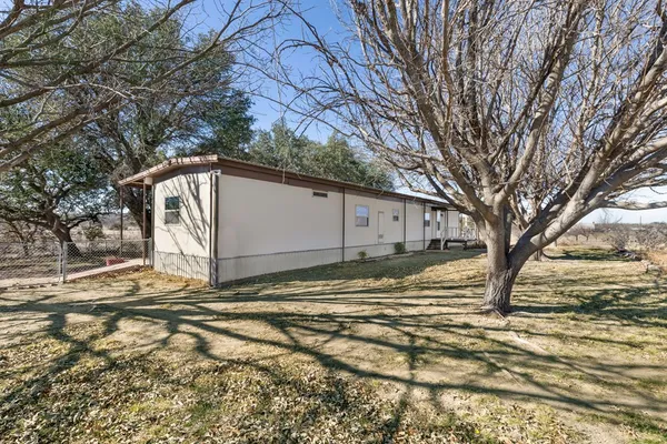 a backyard of a house with large trees and wooden fence