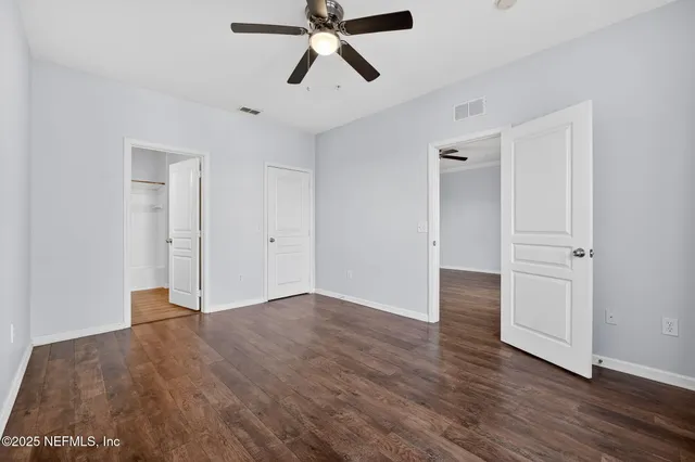 an empty room with wooden floor and ceiling fan