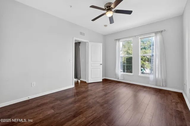 a view of empty room with wooden floor and fan