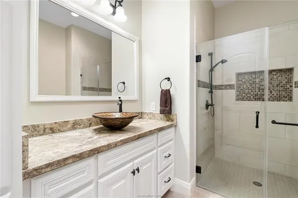a bathroom with a granite countertop sink a mirror and shower