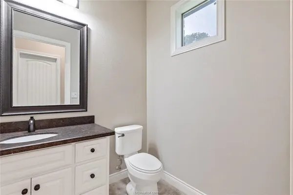 a bathroom with a granite countertop toilet sink and mirror