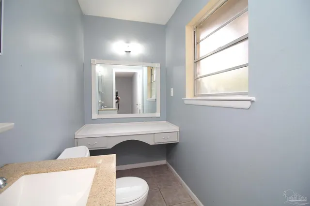 a bathroom with a toilet a sink a window and mirror