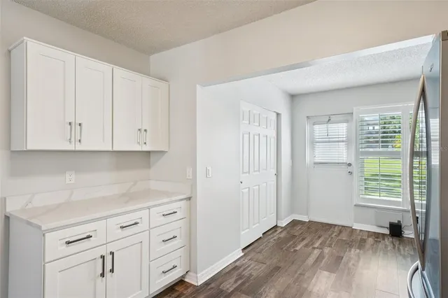 a view of kitchen with granite countertop white cabinets and sink
