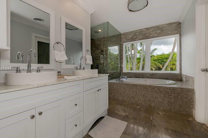 7475 Southwest 134th Street Pinecrest, FL 33156 - Photo 18 of 42 a bathroom with a sink mirror and a bathtub next to a window