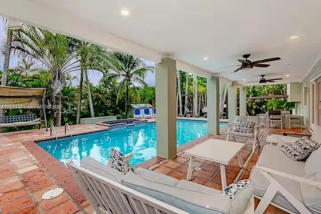 a view of a patio with couches table and chairs with potted plants and large tree