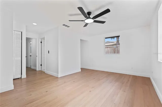 a view of a hallway with wooden floor and a ceiling fan
