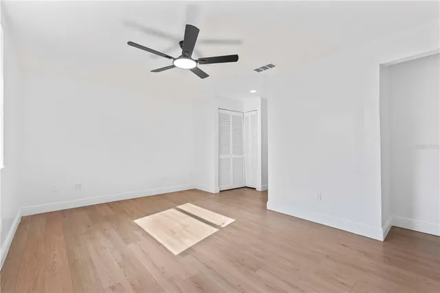 an empty room with wooden floor a ceiling fan and view fan