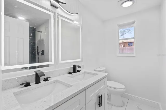 a bathroom with a granite countertop sink mirror vanity and toilet
