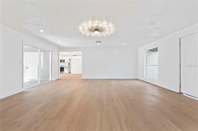 an empty room with wooden floor and chandelier