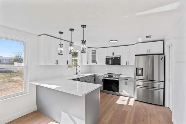 a kitchen with stainless steel appliances granite countertop a refrigerator a sink dishwasher a stove and a refrigerator with wooden floor