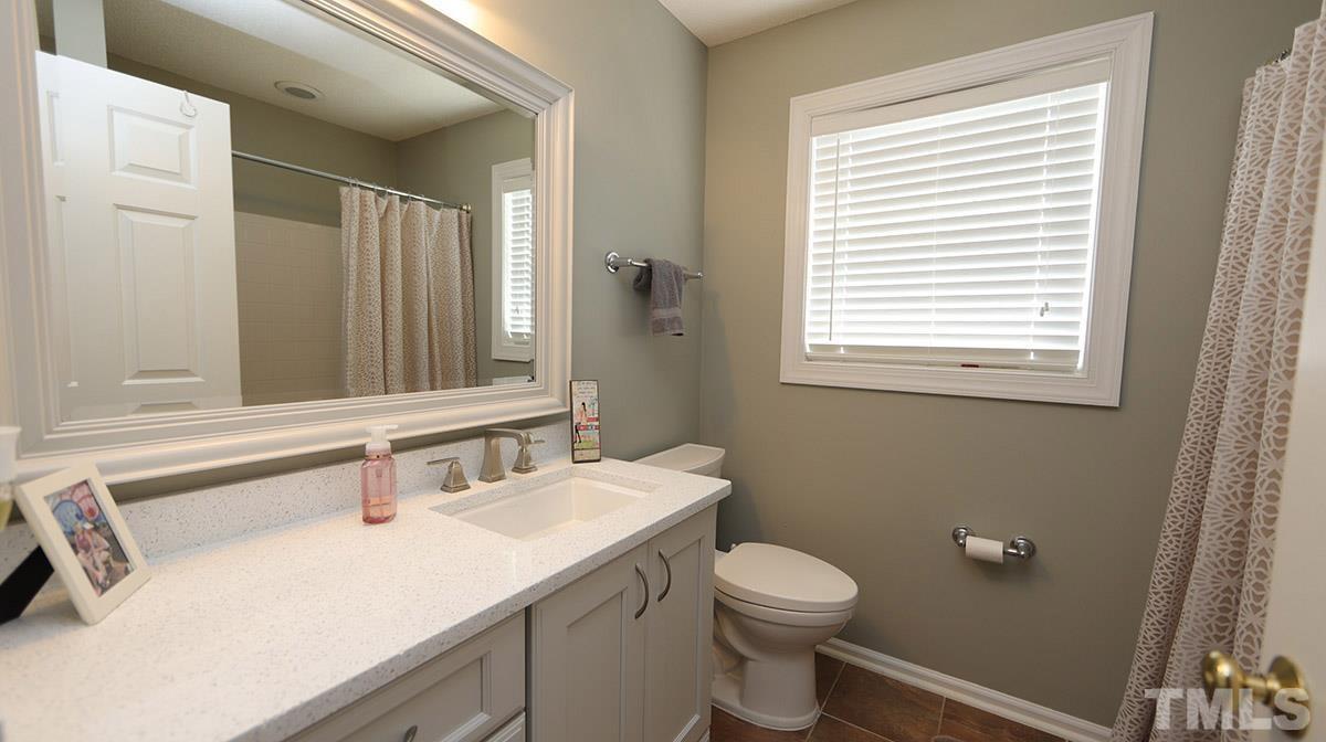 3820 Evander Way Raleigh, NC 27613 - Photo 25 of 30 The upstairs hall bath has a tile floor & new vanity with quartz counters & a framed mirror.