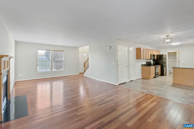 a view of empty room with wooden floor and kitchen