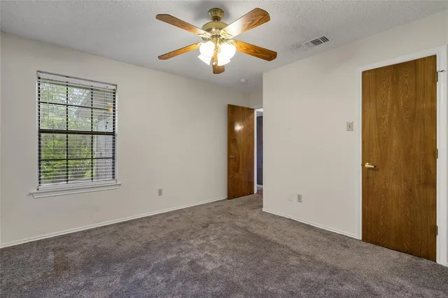 an empty room with windows and fan