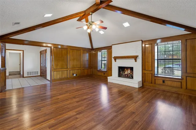 a view of an empty room with wooden floor fireplace and a window