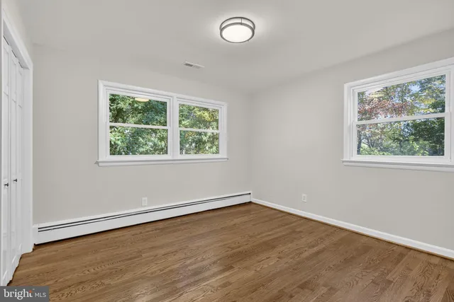 an empty room with wooden floor and windows