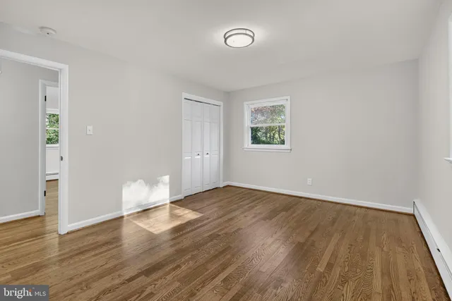 an empty room with wooden floor fireplace and windows
