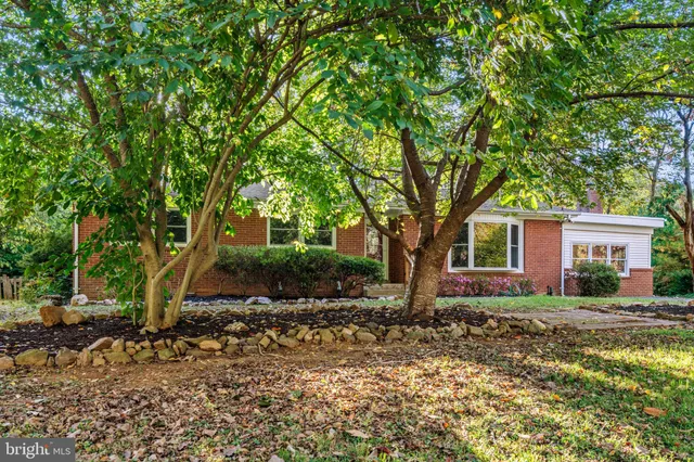 a front view of a house with a garden and trees