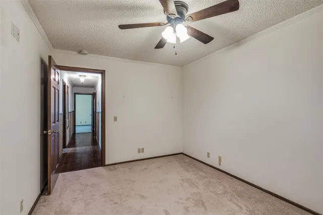 an empty room with a chandelier fan and windows