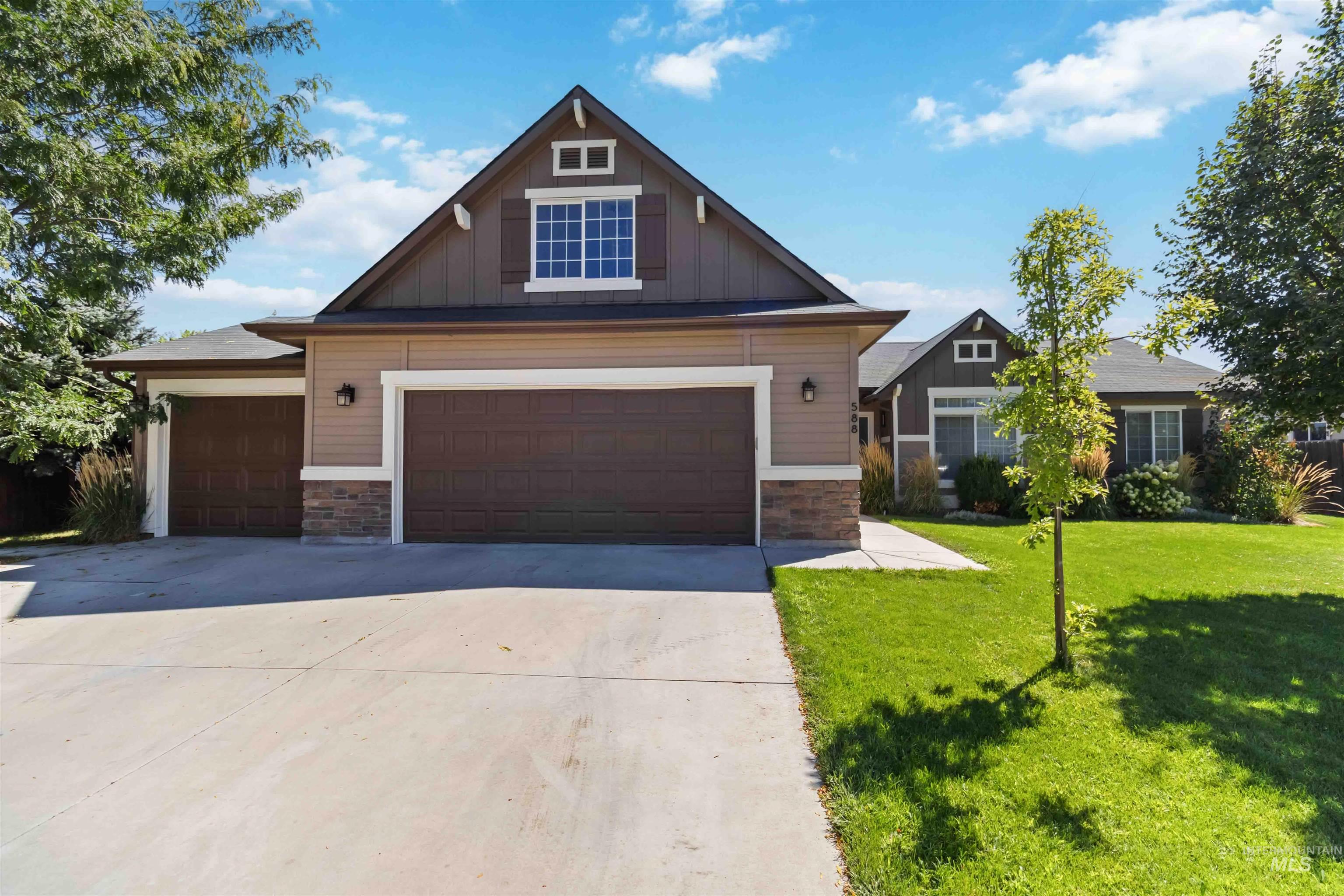 Craftsman house with stone siding, board and batten siding, driveway, and a front lawn