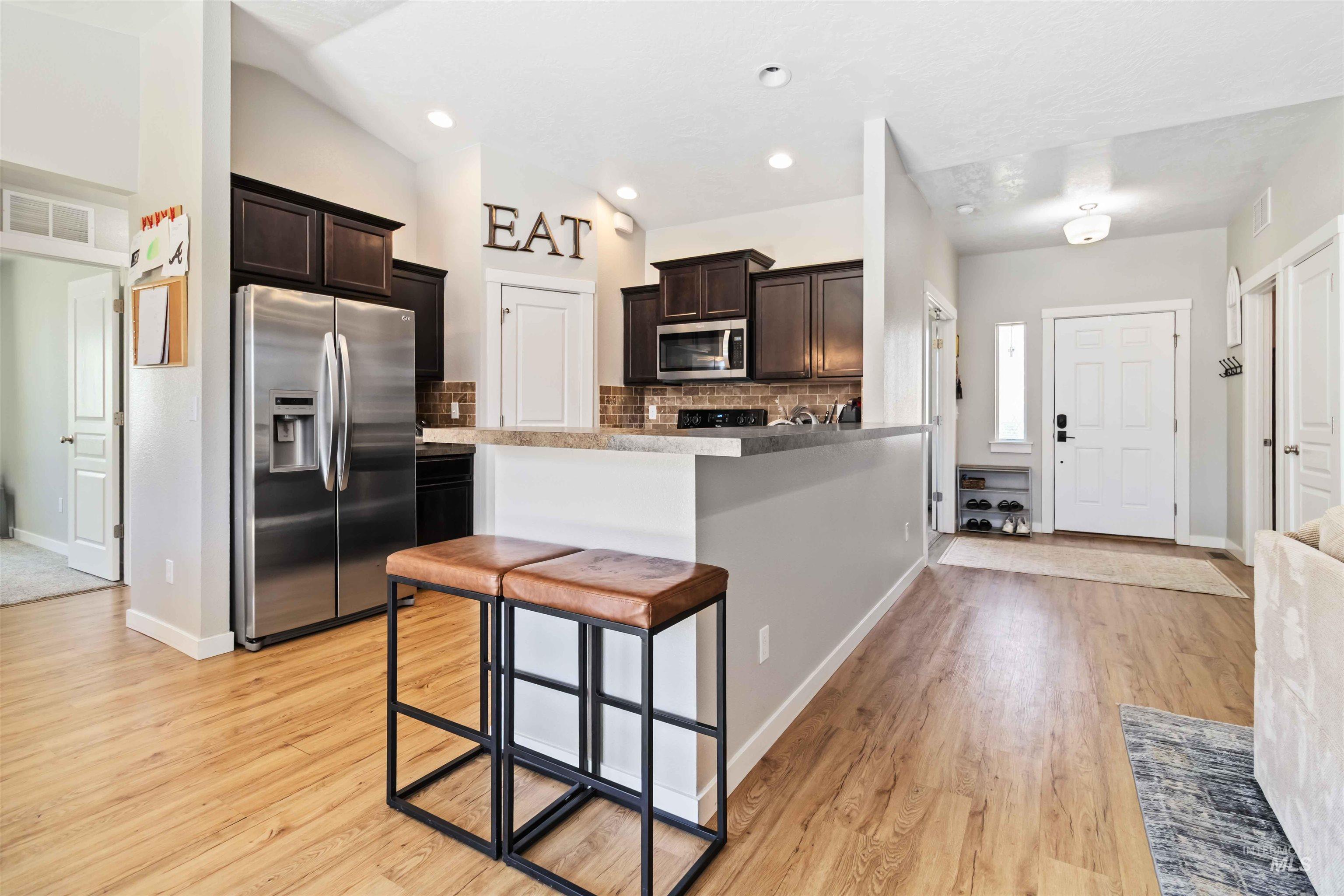588 Gateway Avenue Middleton, ID 83644 - Photo 18 of 42 Kitchen featuring stainless steel appliances, tasteful backsplash, dark wood finish cabinets, a breakfast bar area, and light wood-style floors